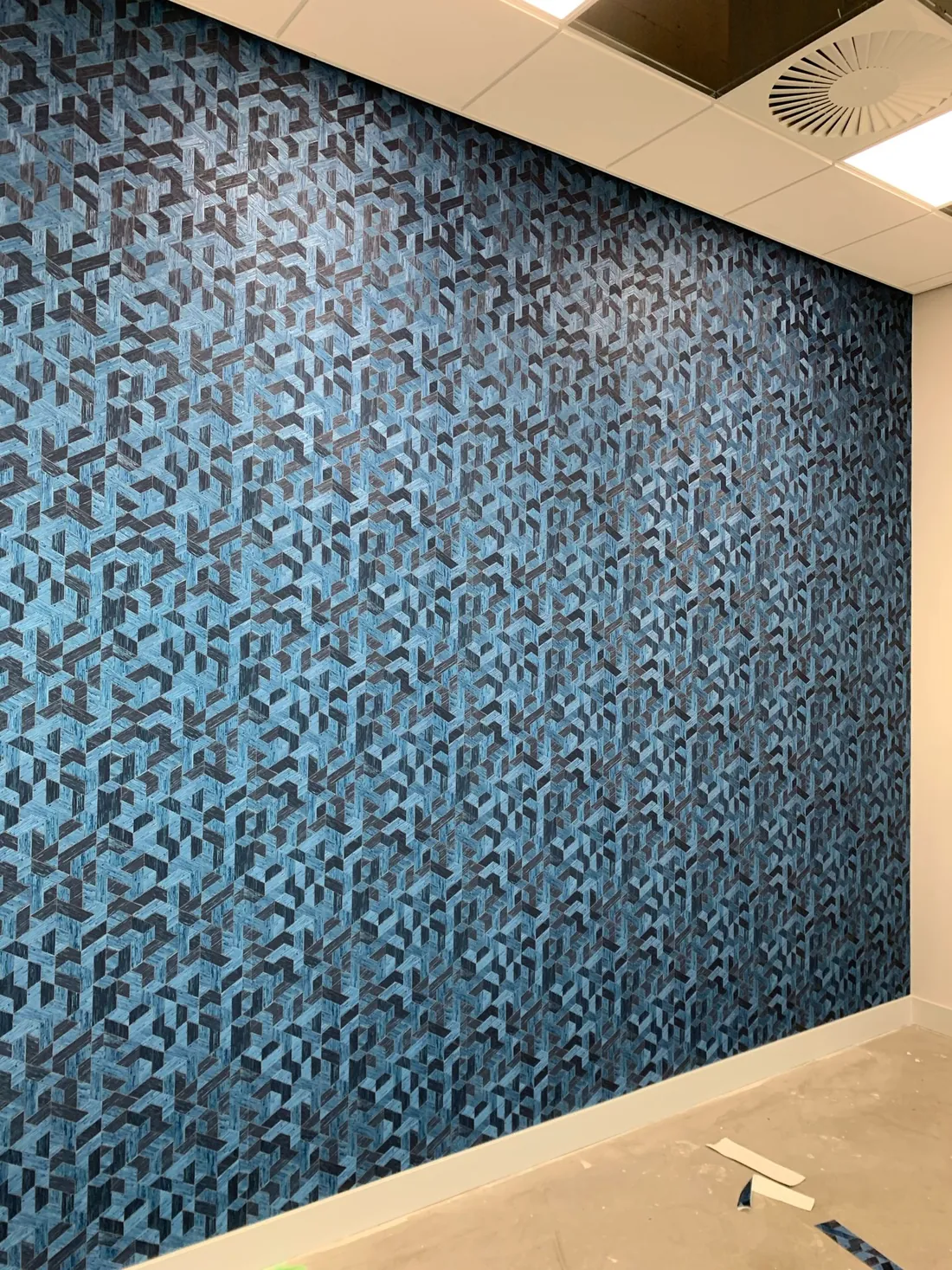 Blauw Arte-behang met grafisch geometrisch patroon over een volledige wand